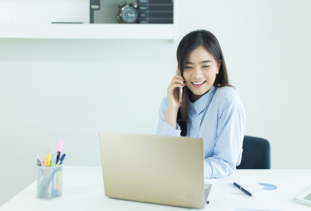 A woman sitting at her office desk talking on the phone